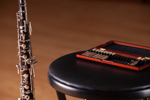 Musical instrument parts and chair in front of a brown background.