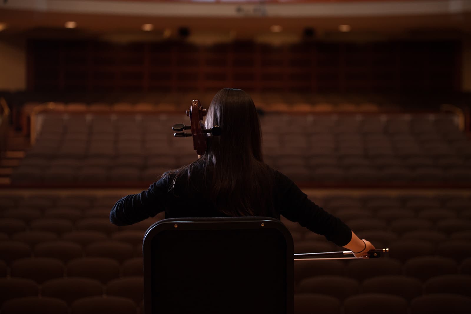 Artist performing in an empty hall with their back facing he camera.