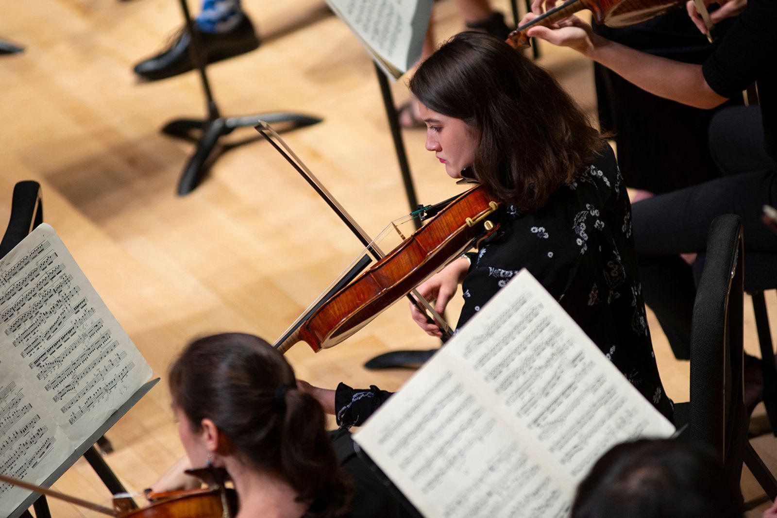 Two women in an orchestra play violins.