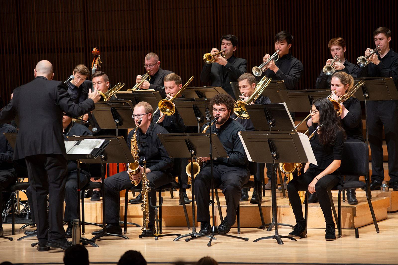 Students perform with an array of instruments on stage.