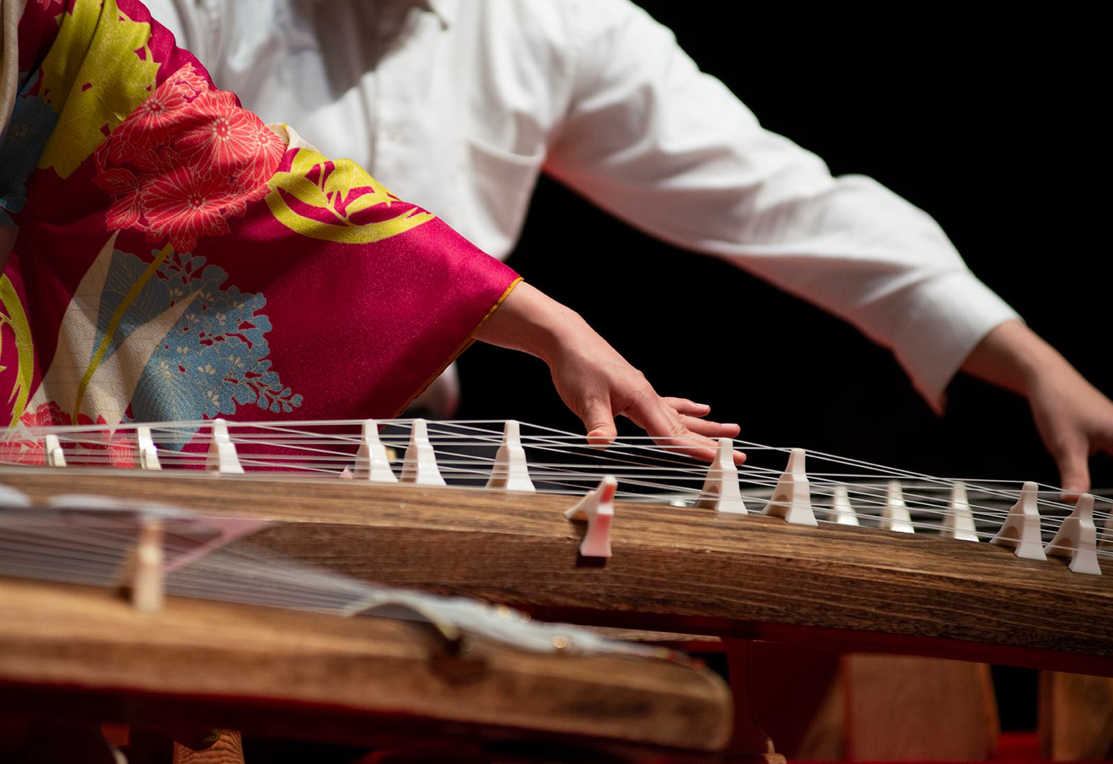 Two people play the koto, a traditional Japanese string instrument..