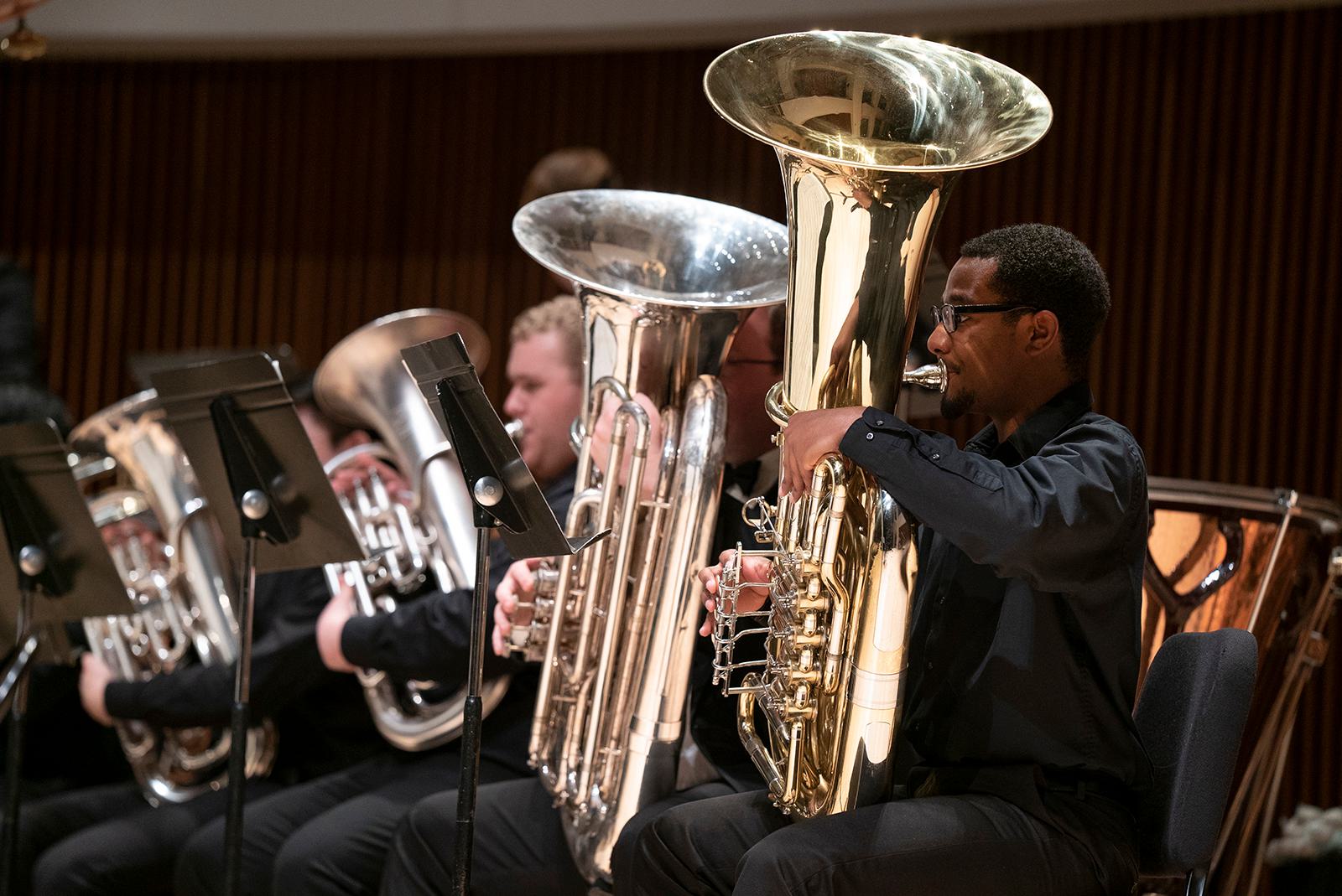 Members of the UMD Wind Ensemble play tubas during a concert.