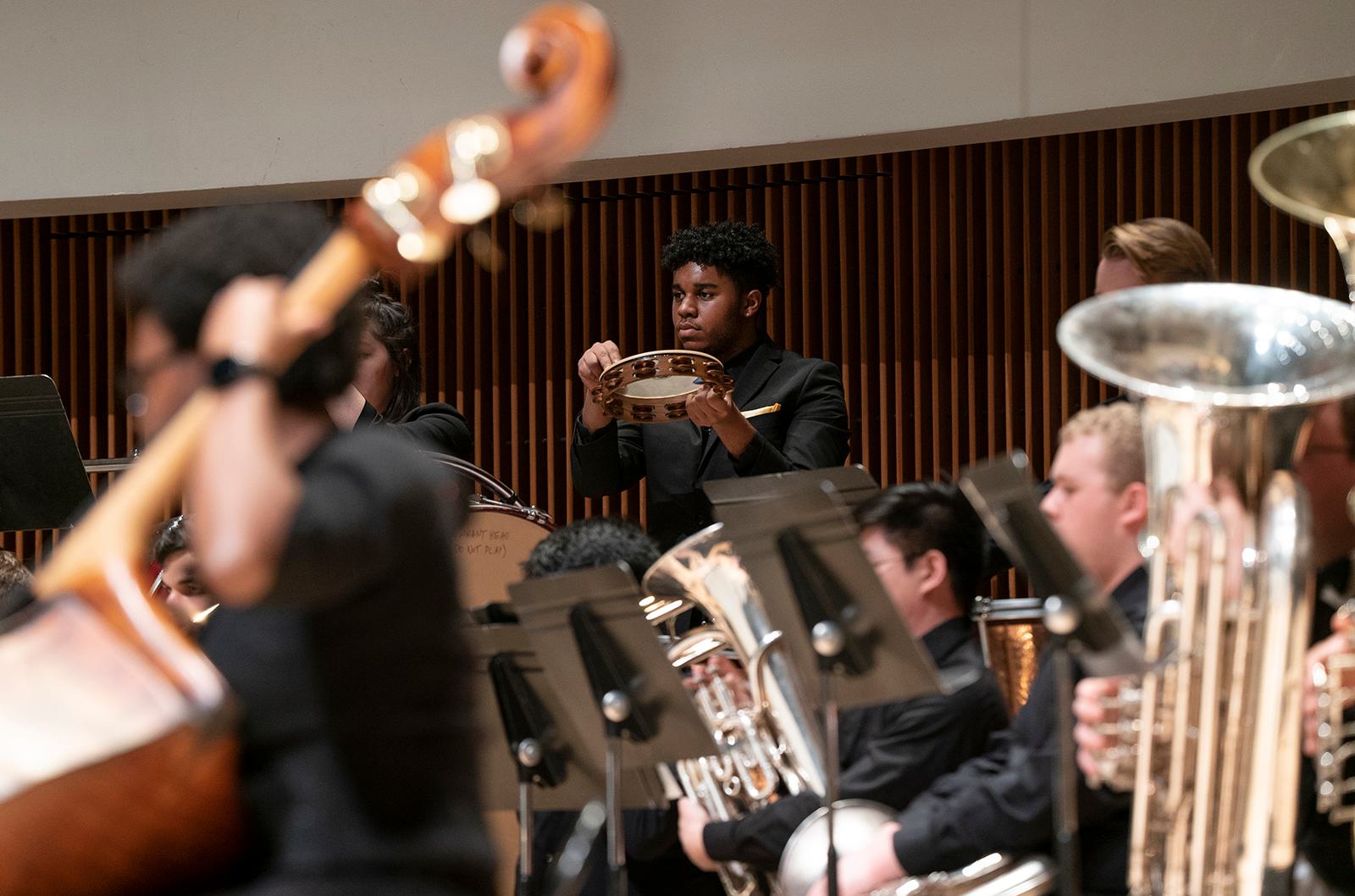 Members of the UDM Wind Ensemble perform on stage.