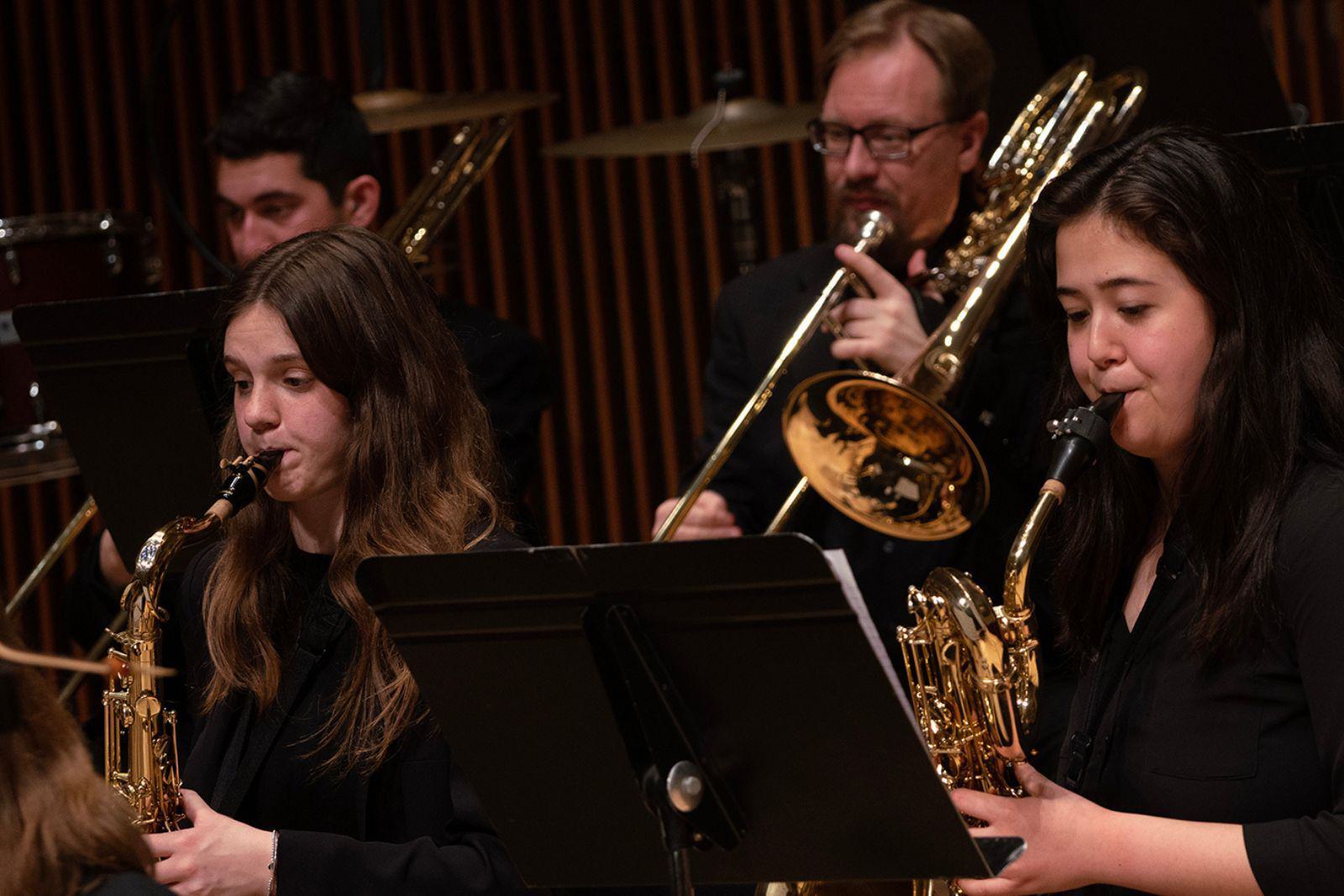 Students in an orchestra play brass instruments.