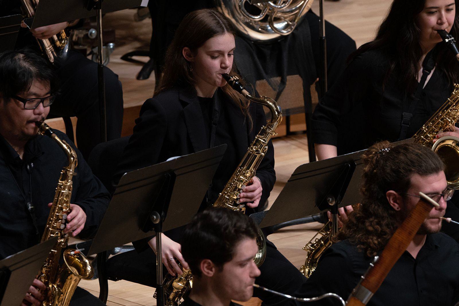 Students play orchestral instruments.