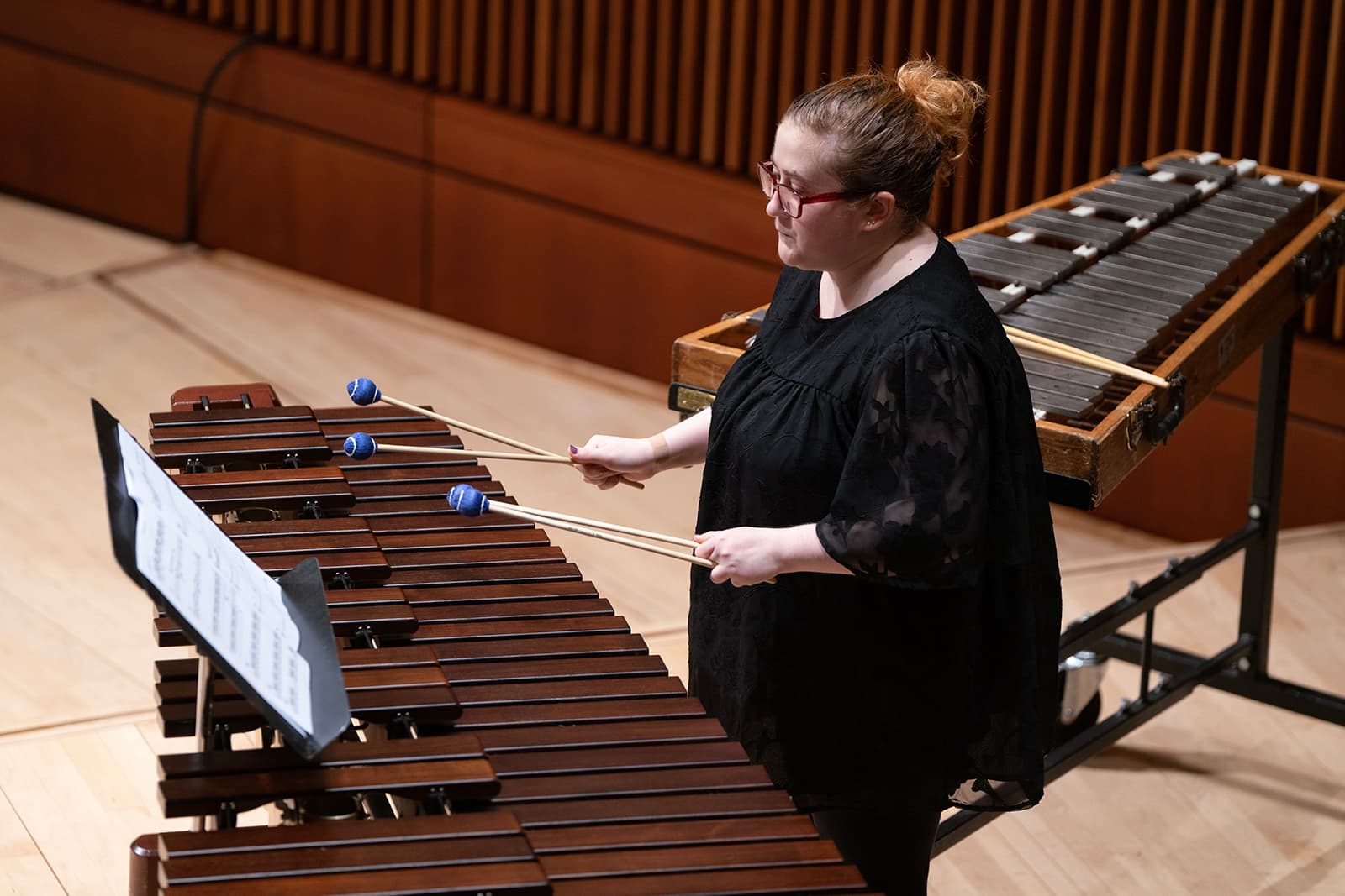 Student artist with glasses performing in a concert hall..