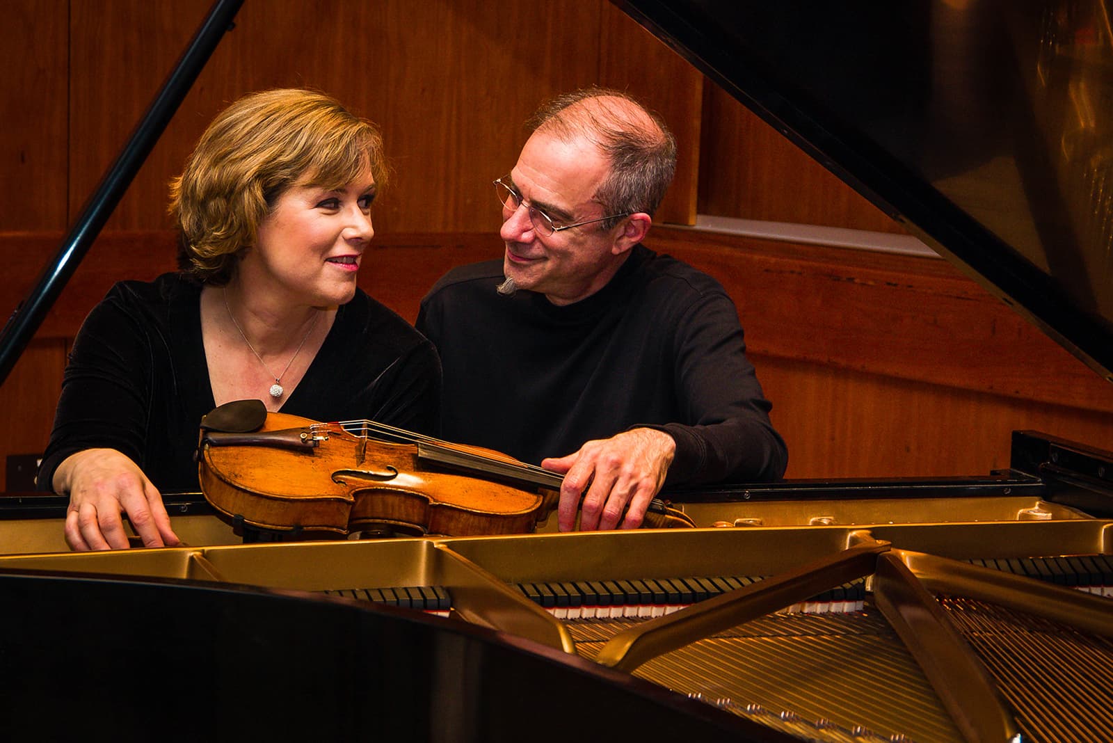 Two musicians sitting in front a of a piano.