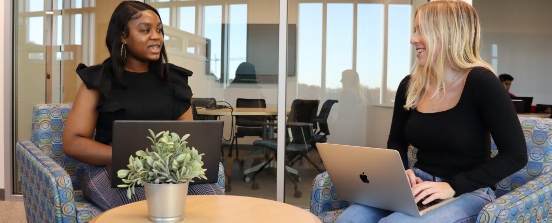 Two people sitting in chairs conversing
