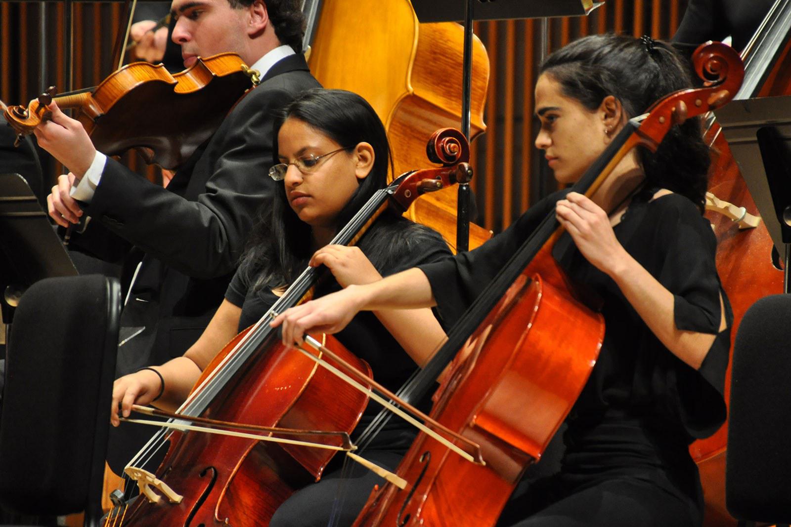 Two women play cellos on stage.
