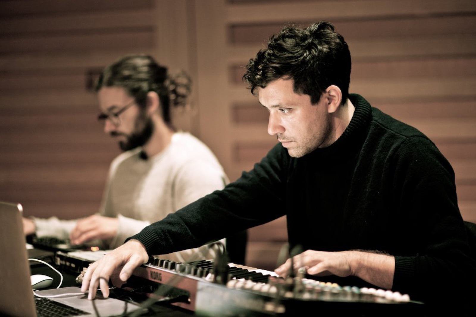 A man uses a digital piano and a computer.