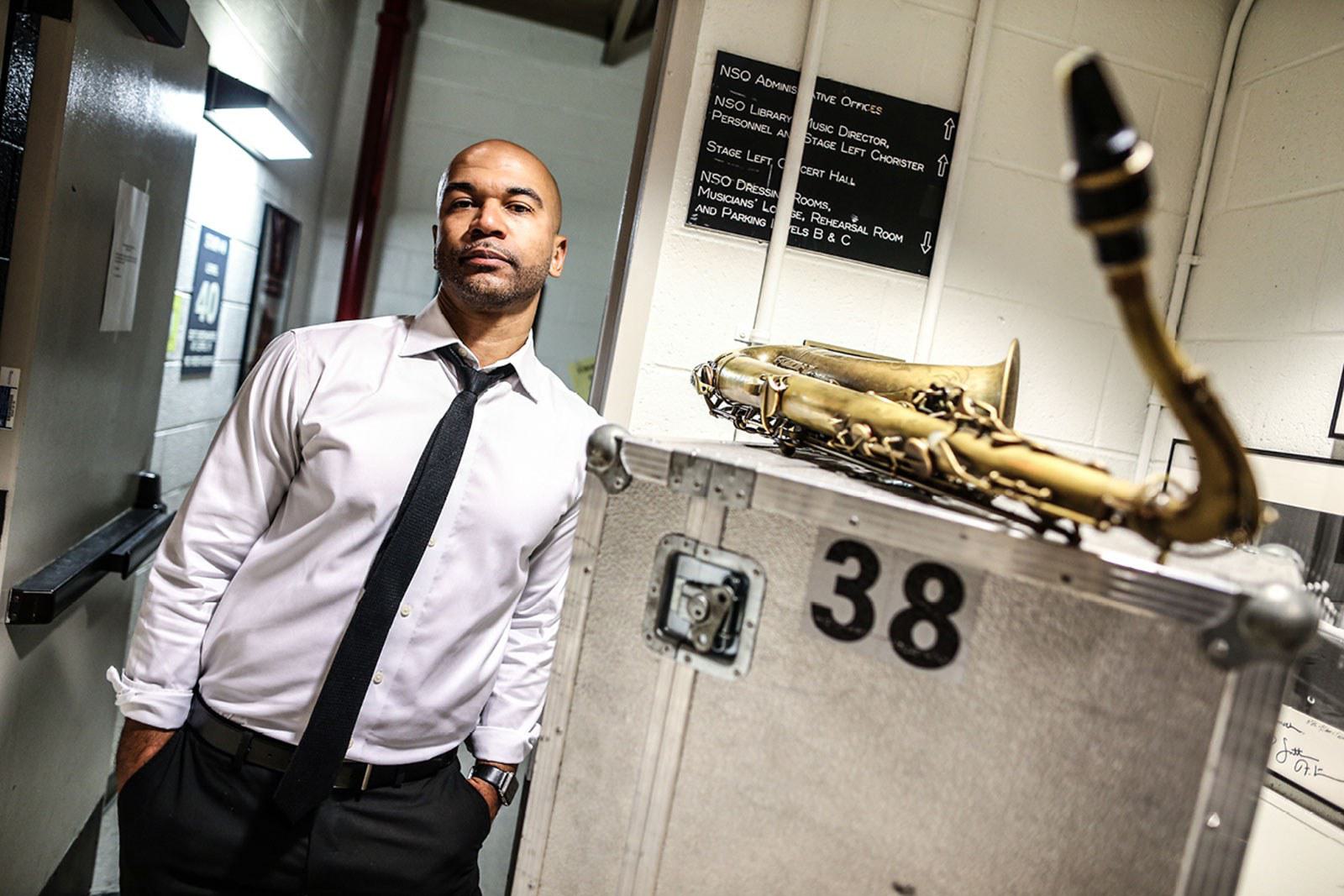 Man poses for picture with saxophone.