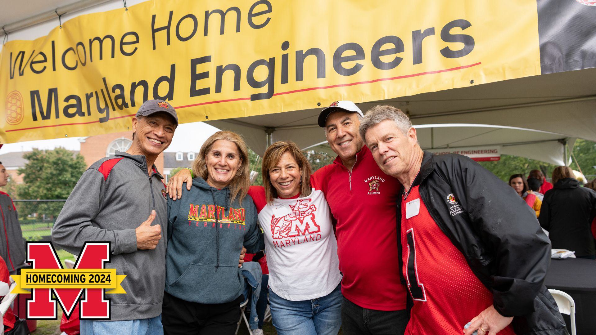 A group of Maryland Engineering alumni posing and smiling together under a tent.