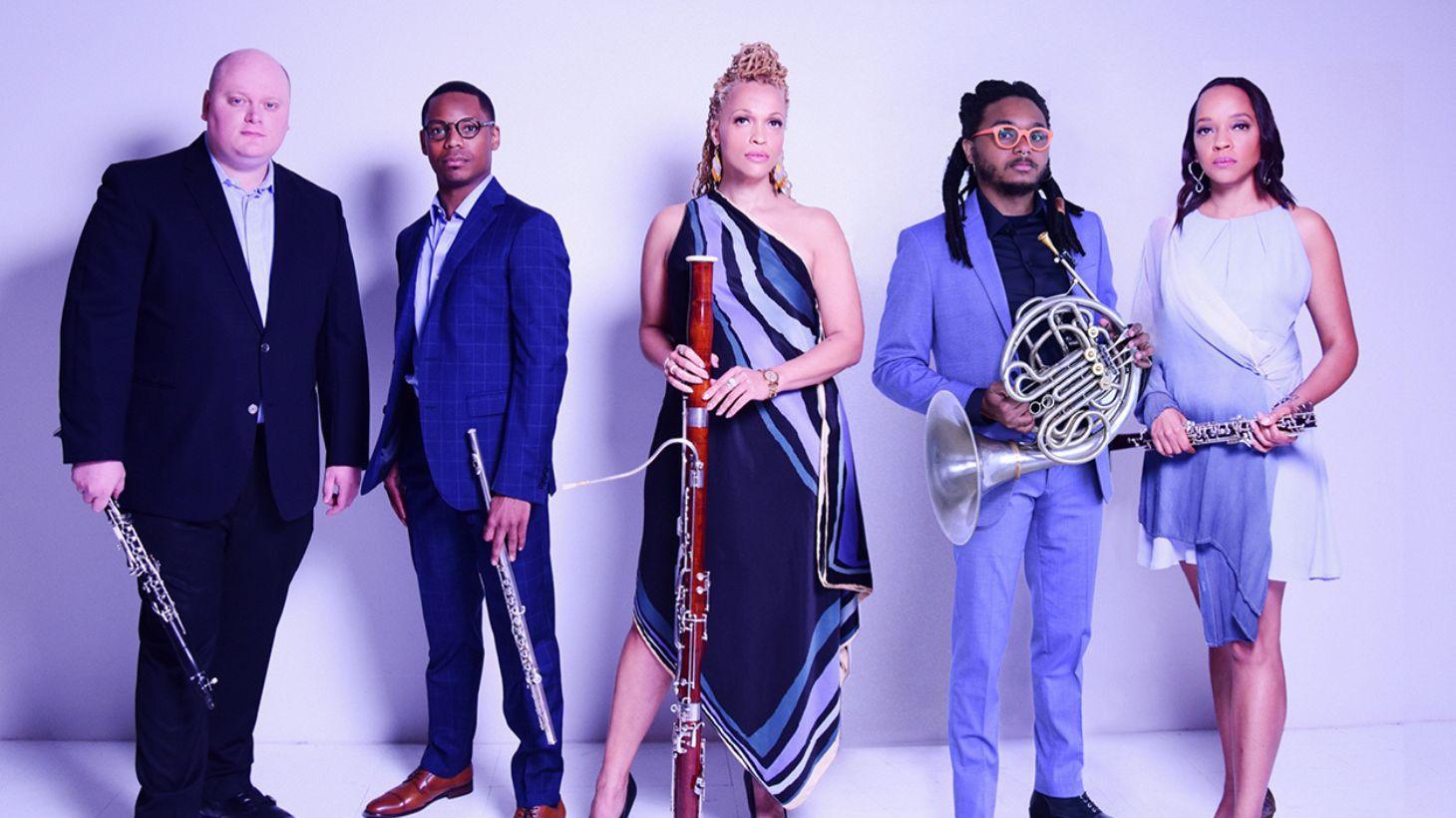 Members of Imani Winds quintet pose with their wind instruments.
