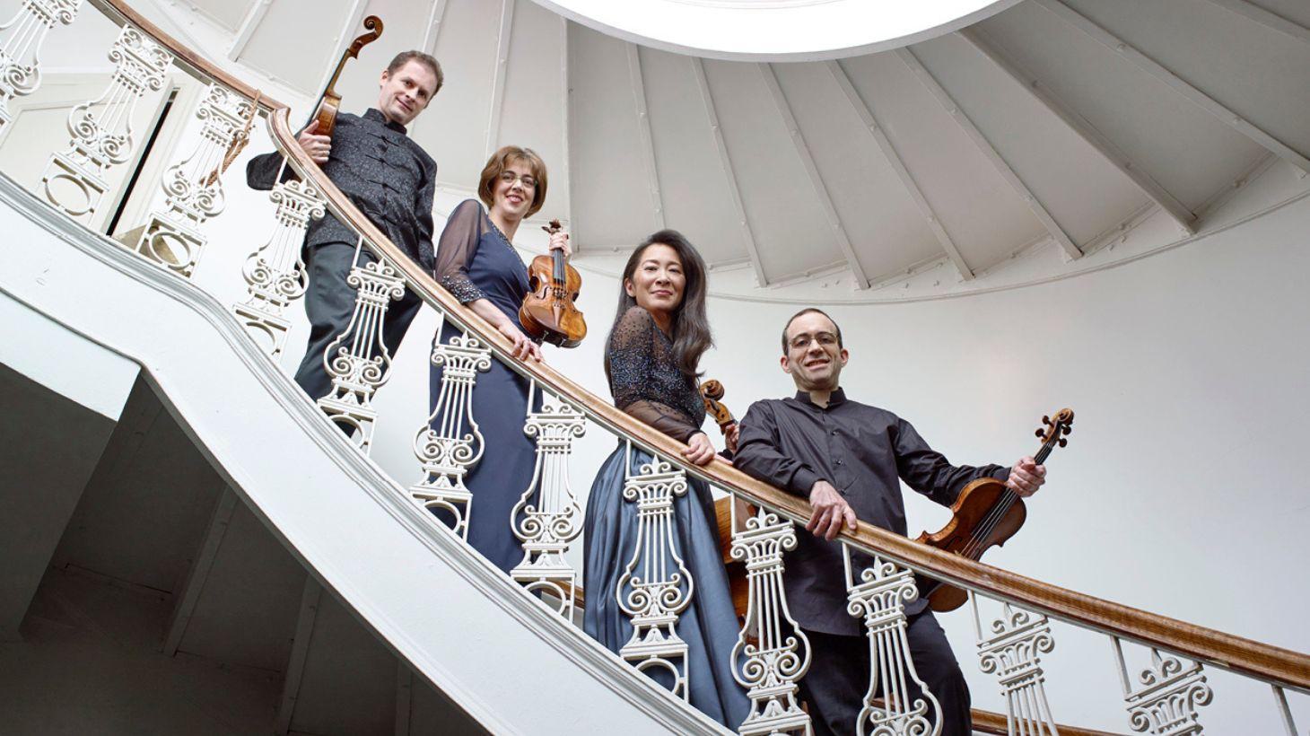 Members of the Brentano Quartet pose on an elegant staircase.