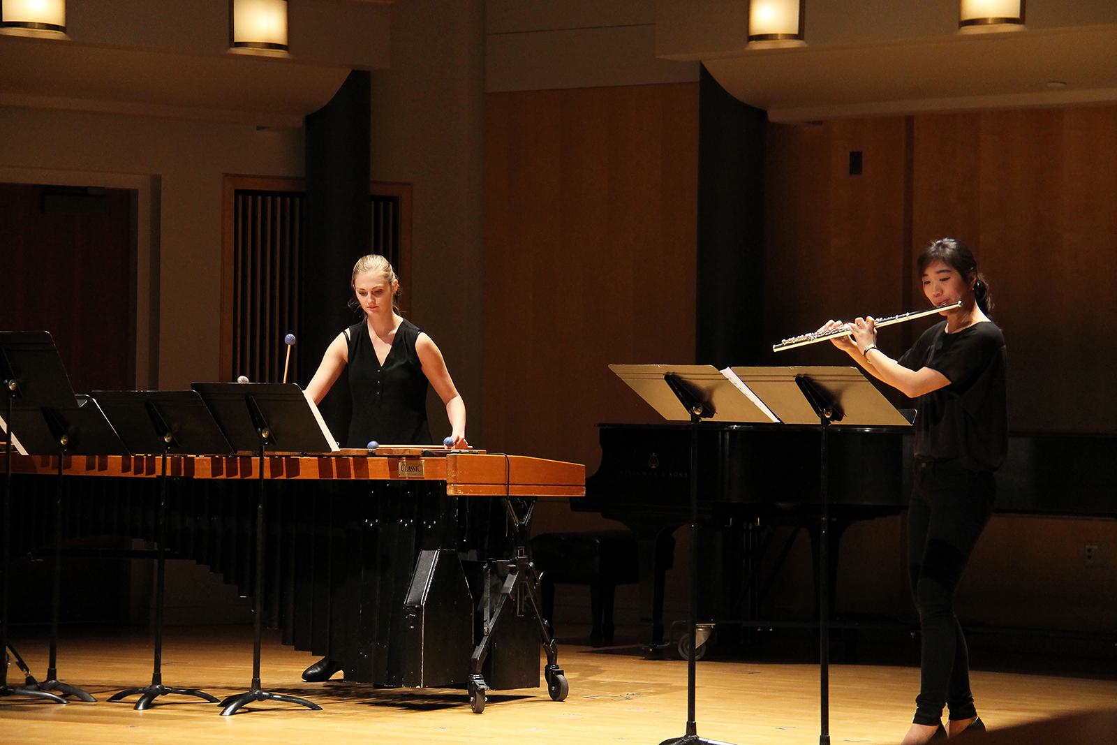 Two musicians performing in a hall.