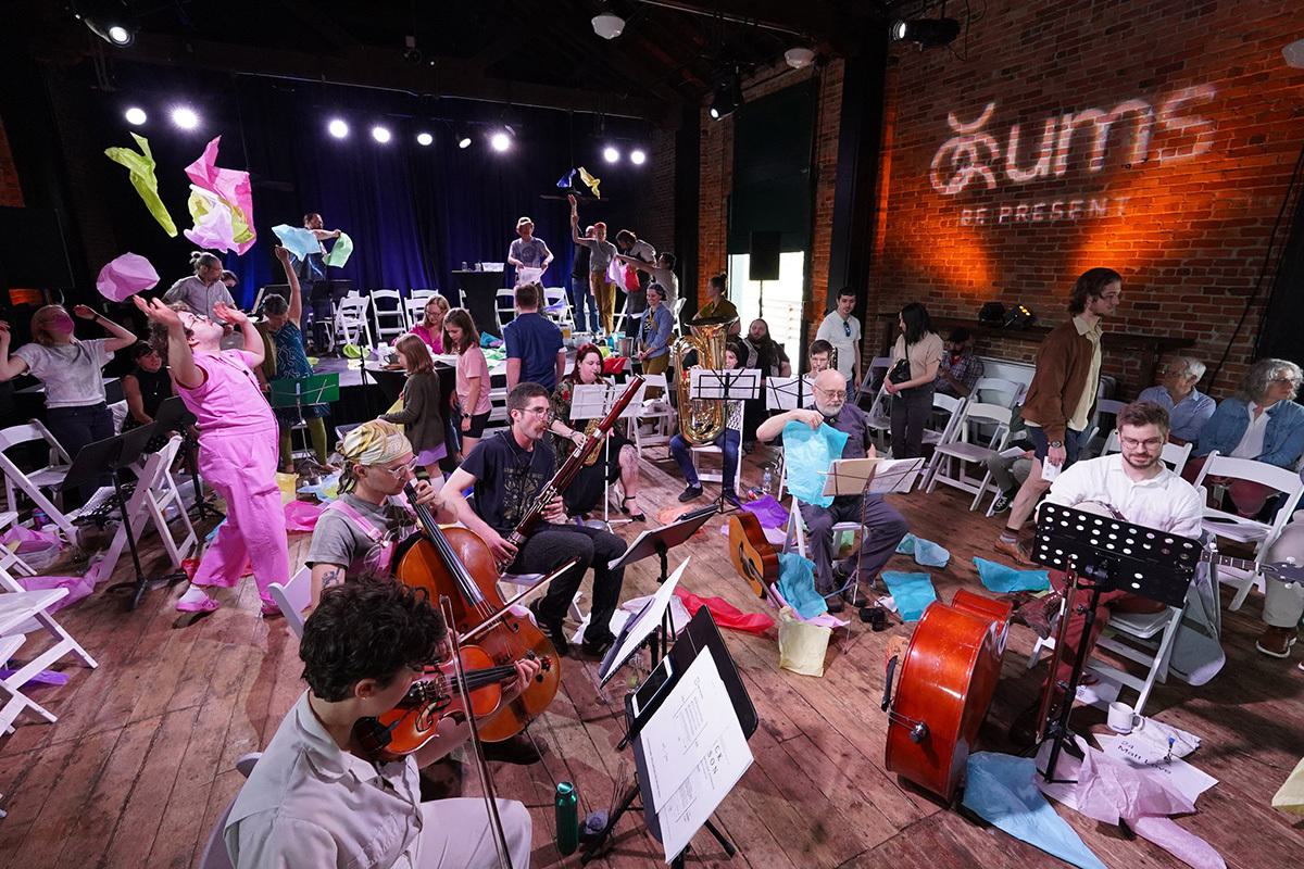 People playing instruments and one women throwing colorful papers in the air