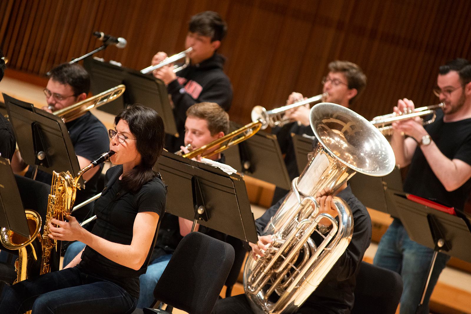 Ensemble members play various brass instruments on stage.
