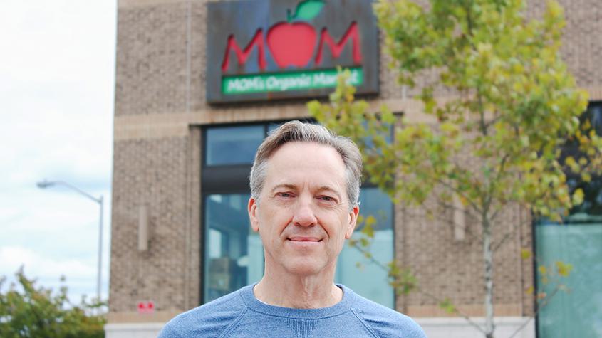 Image of CEO Scott Nash in front of a MOM's grocery store