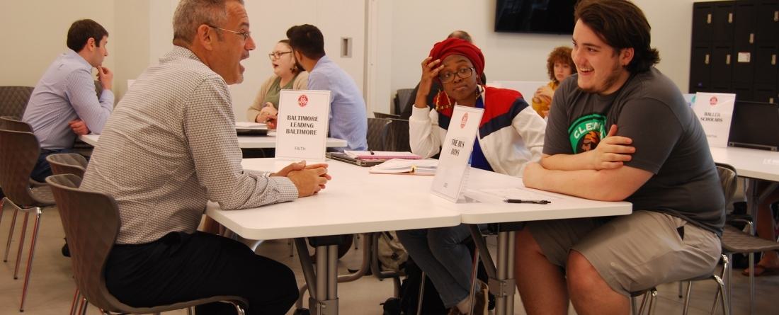 Three people sitting at table talking