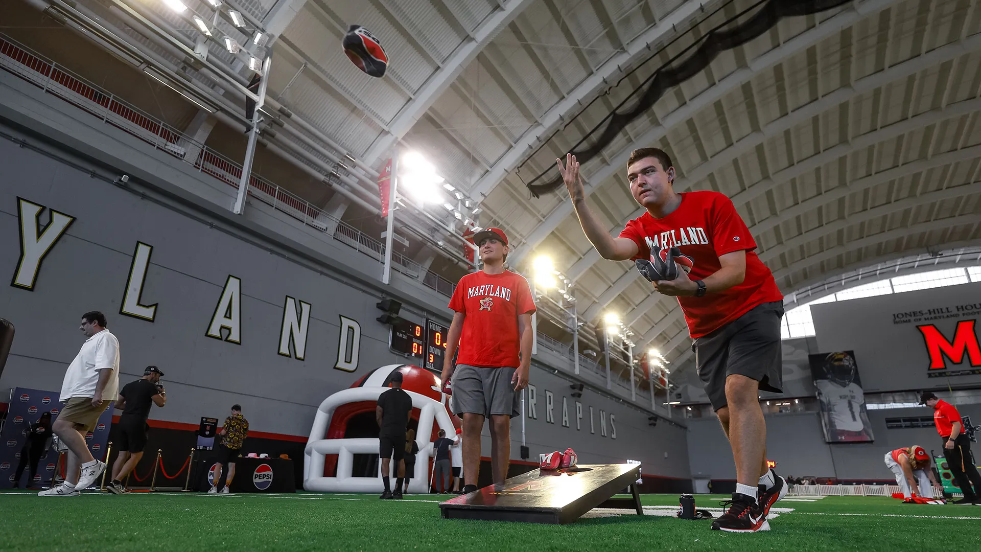 Guests play a game of cornhole at Terpsville Fan Fest located at the football indoor practice facility.