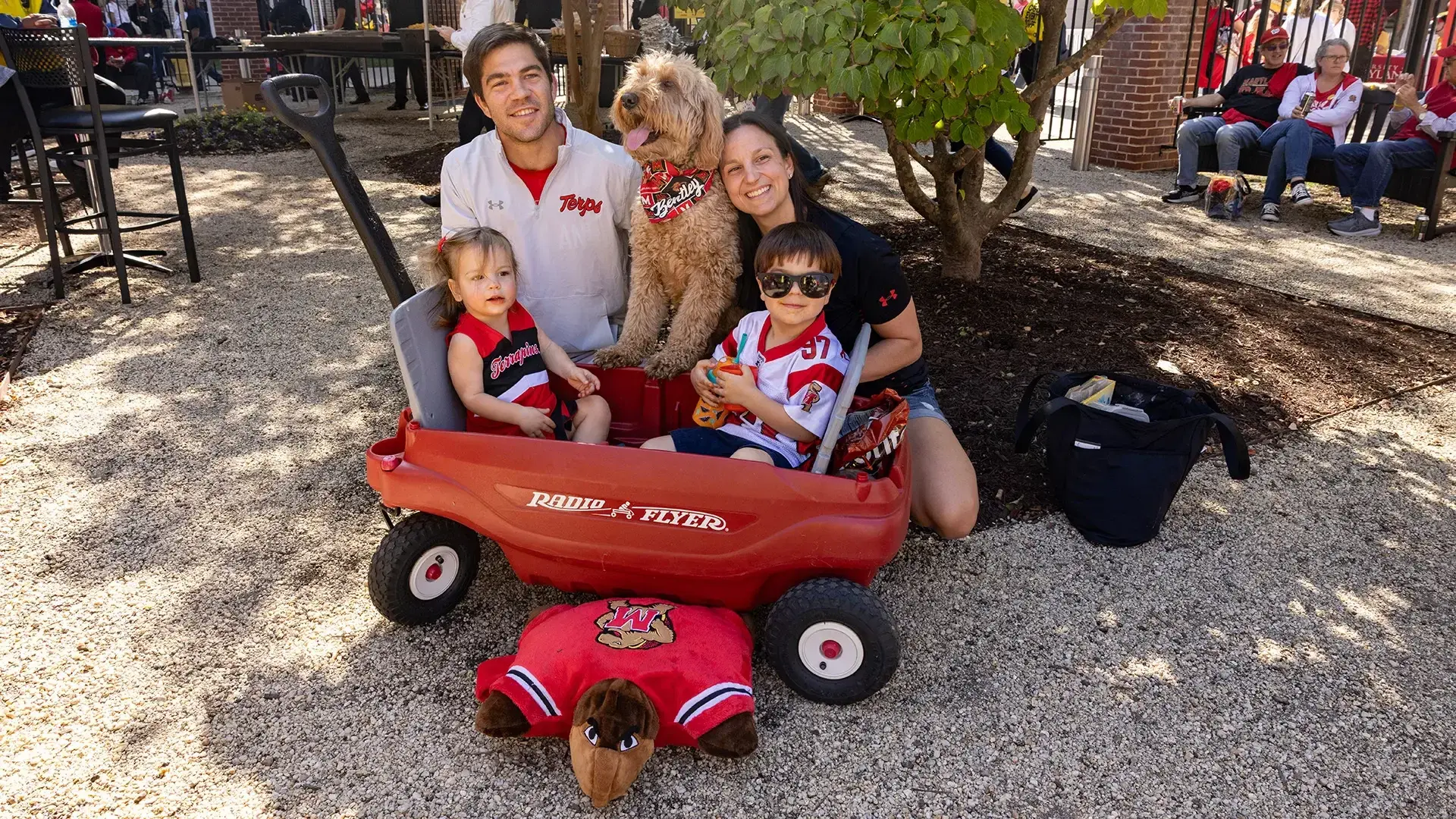 Family with young children and a dog with Maryland Terrapins gear on, at a park.
