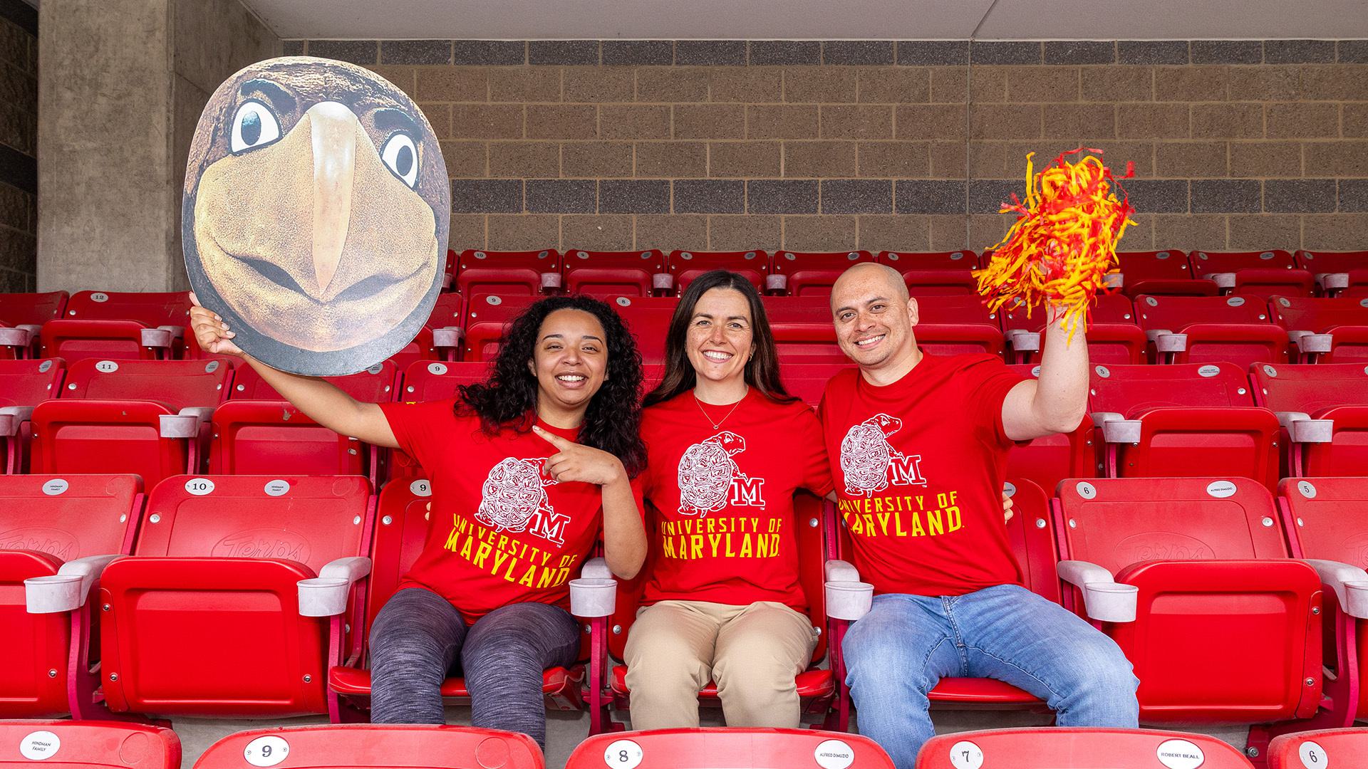 Three graduates pose wearing the official Homecoming 2025 t-shirt.