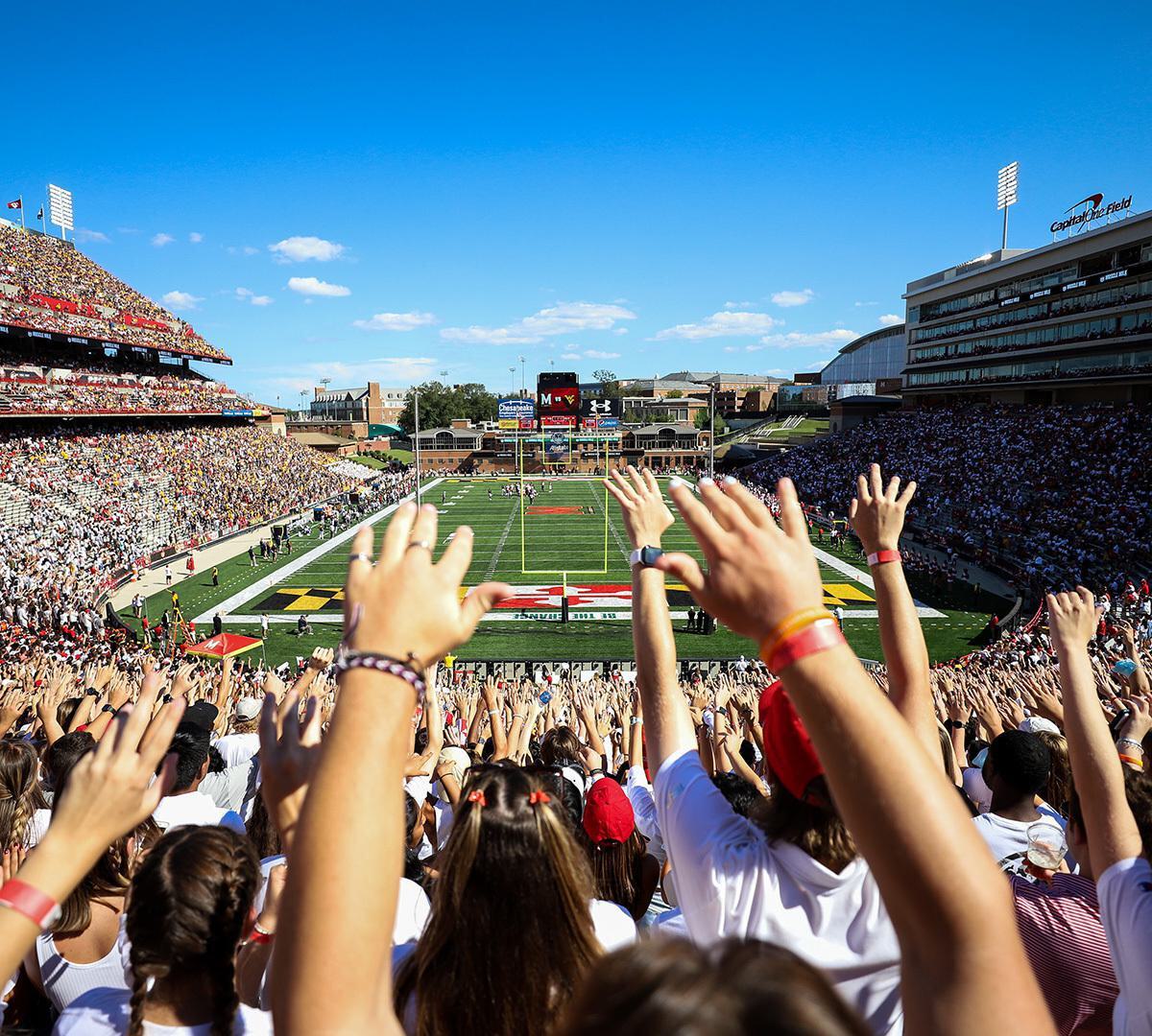 Fans raise their hands in the stands at SECU Stadium.