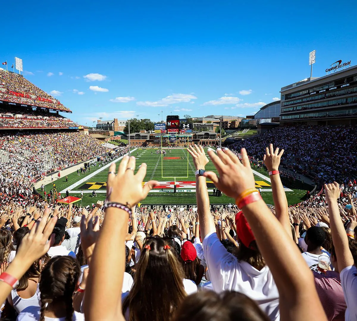 Fans raise their hands in the stands at SECU Stadium.