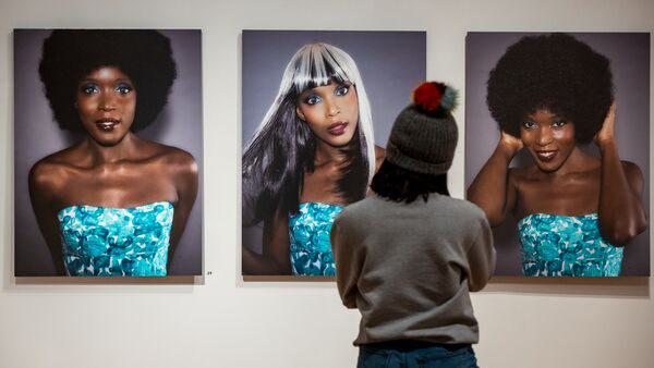 University of Maryland sophomore Denise Agyeman looks at prints by Adamants Delphine Fawundu, (left to right) "Blue Eyes, Cocoa Brown," "Pecola's Blues" and "Big Fro, Brown Eyes" on display in the exhibition "Posing Beauty in African American Culture" exhibition at the David C. Driskell Center for the Study of the Visual Arts and Culture of African Americans and the African Diaspora