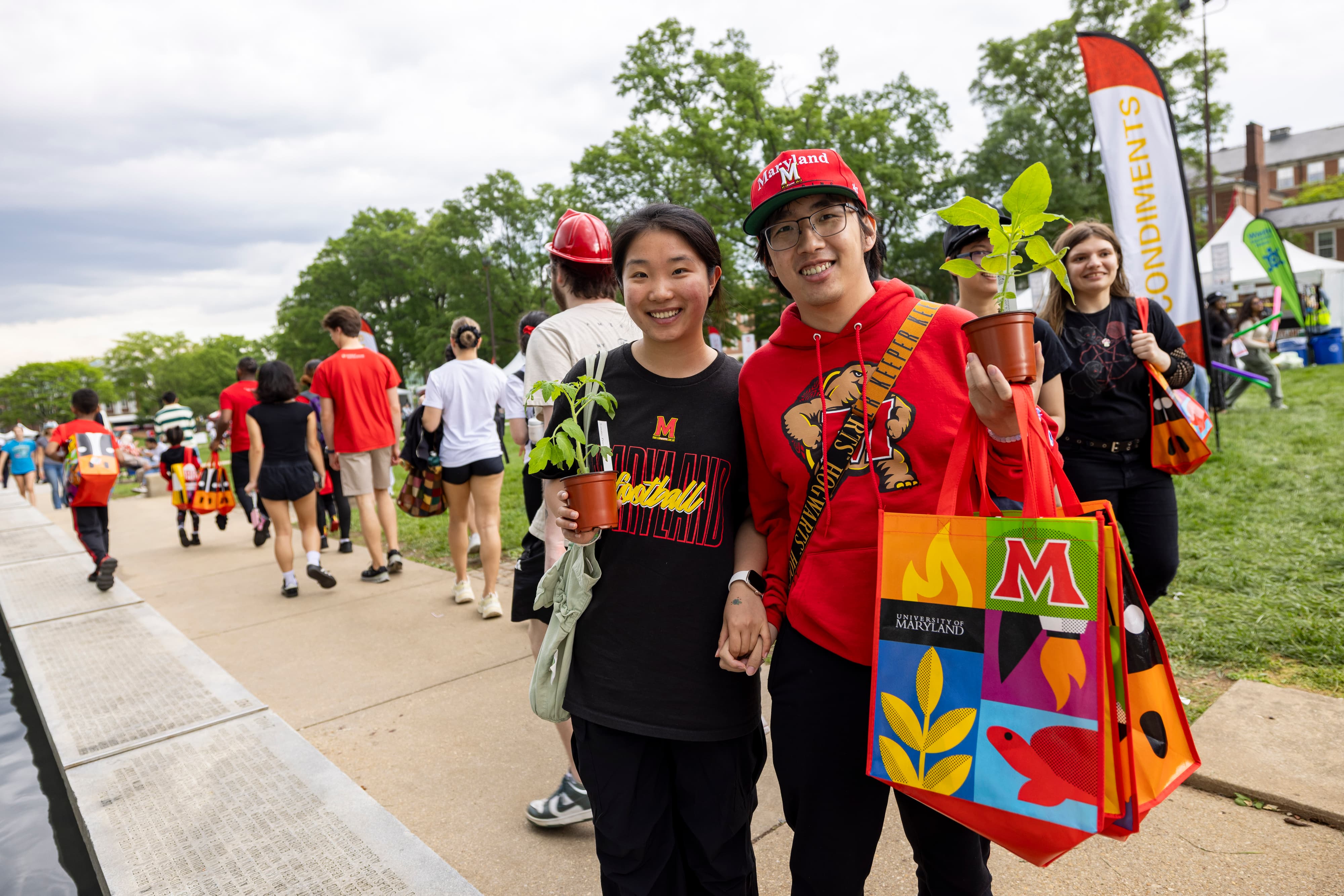 Visitors to Maryland Day 2025 hold up giveaway plants
